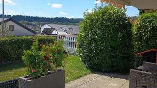 Sonnige Terrasse der Ferienwohnung mit Markise, Sitzgelegenheiten und Garten