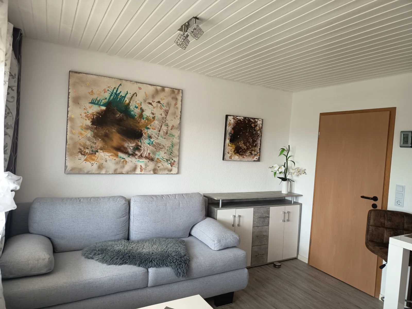 Heller Wohnbereich der Ferienwohnung mit Sofa und Kunstwerken an der Wand