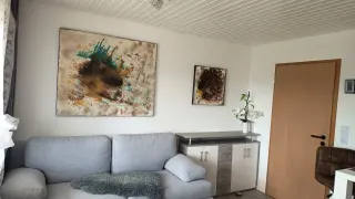 Heller Wohnbereich der Ferienwohnung mit Sofa und Kunstwerken an der Wand